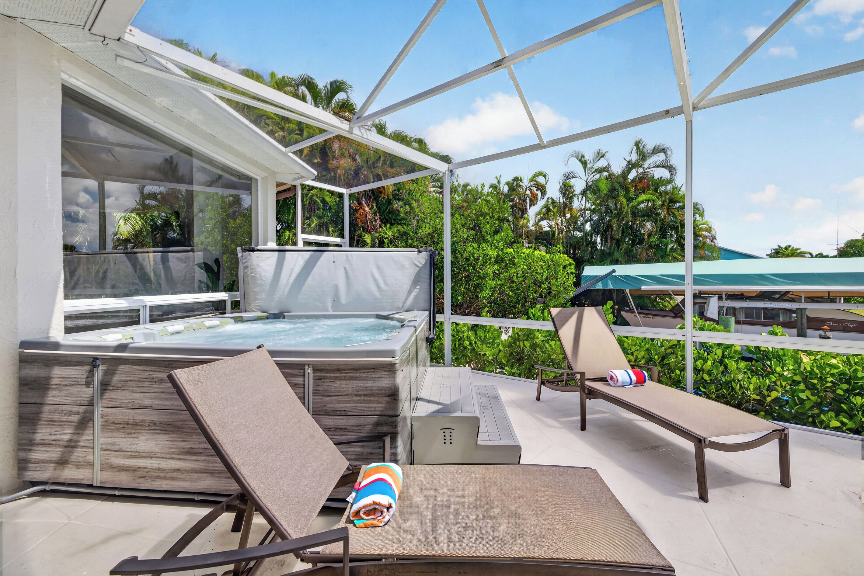 Un espace extérieur abrité comprenant un jacuzzi, des chaises longues et une vue sur l’océan.