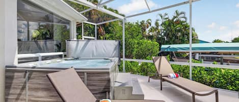 Un espace extérieur abrité comprenant un jacuzzi, des chaises longues et une vue sur l’océan.