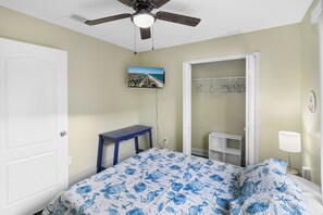 Ein Schlafzimmer mit einem Bett, einem Schreibtisch, einem Kleiderschrank und einem Deckenventilator.