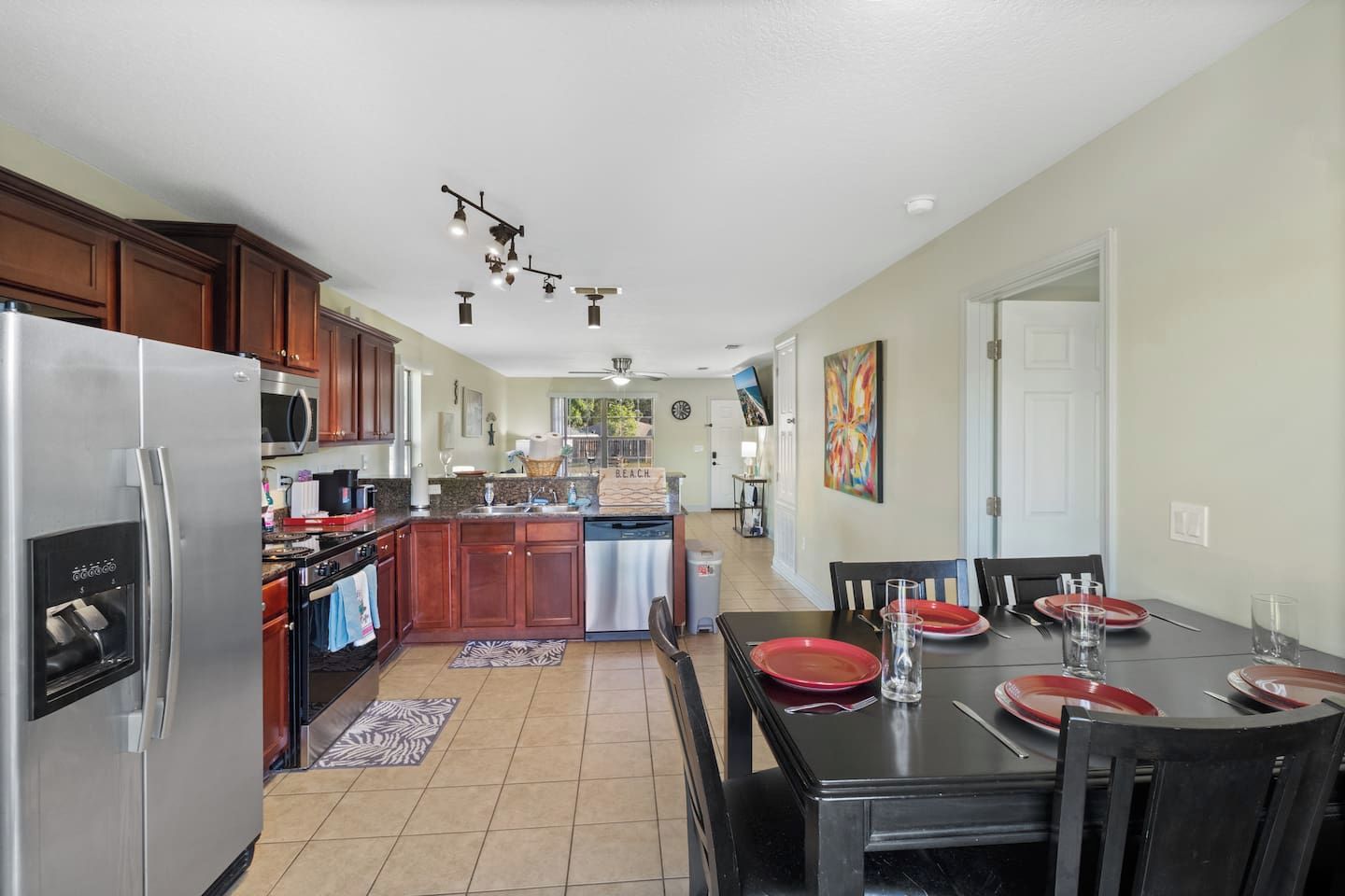 A modern kitchen with stainless steel appliances, wooden cabinets, and a dining area with a table set for four.