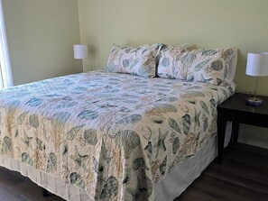 A bed with a floral bedspread, two bedside lamps, and a nightstand with a lamp. - Short Drive to Beach | Pool Table + Fenced Yard (Navarre)