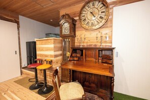 Ein Holzinterieur mit einer großen Wanduhr, einer Bar mit Hockern und einem Vintage-Schrank.