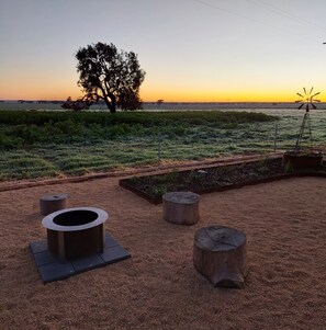 A garden with a tree, a windmill, and a metal planter.