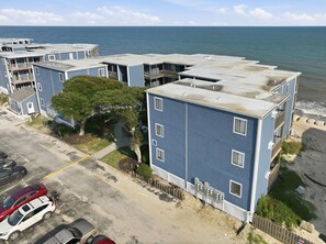 Ein Apartmentkomplex direkt am Strand mit mehreren Wohneinheiten, einem Parkplatz und Blick aufs Meer.