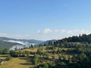 Paisatge rural amb turons suaus, cel serena i una carretera que serpenteja pel terreny.