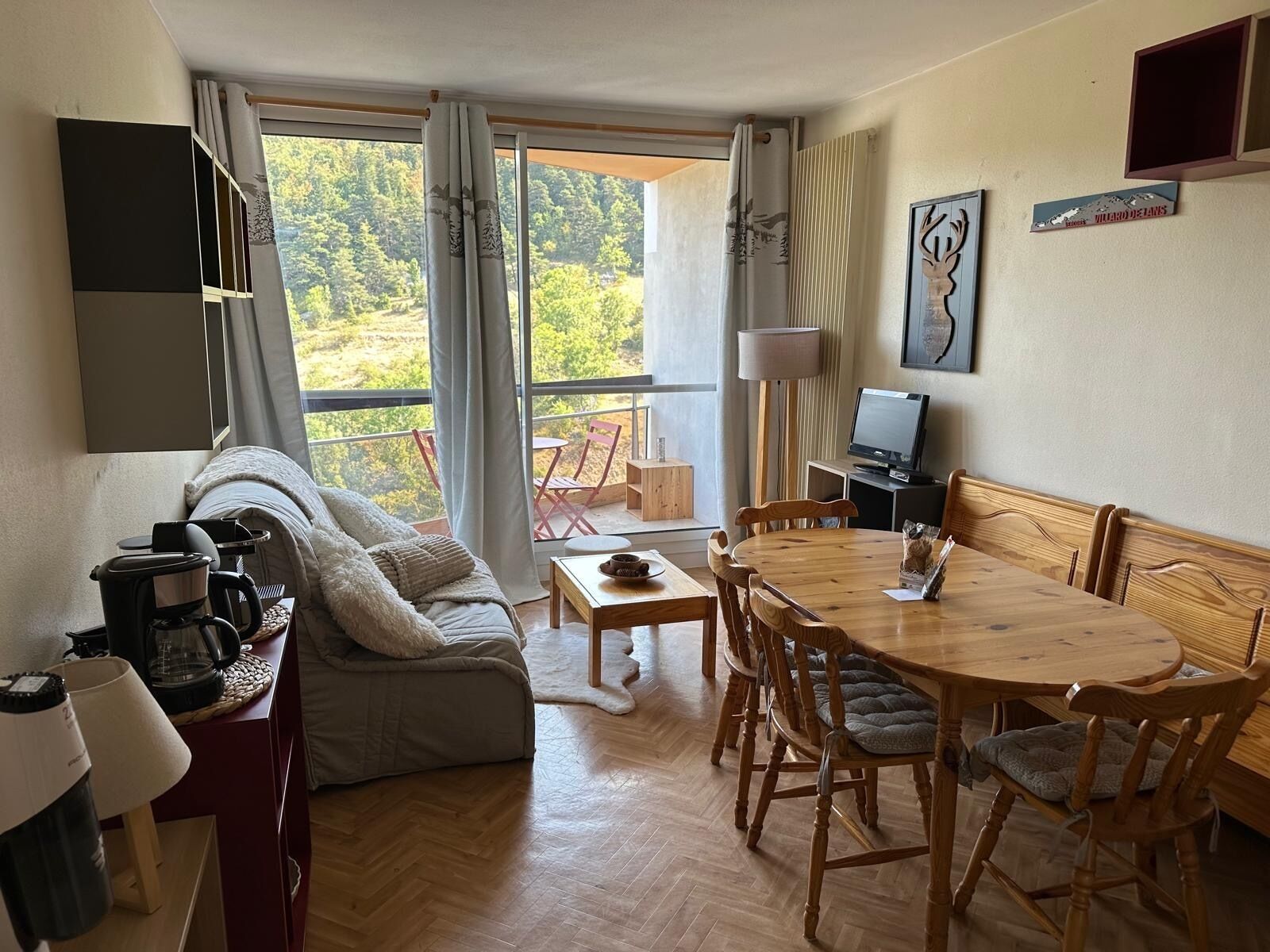 A cozy living area with a sofa, coffee machine, dining table, and chairs.