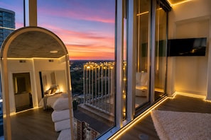 A modern interior with a large window, a sofa, and a TV. - Cozy Lux Studio with Rooftop Pool and Balcony Overlooking the City  (Atlanta)
