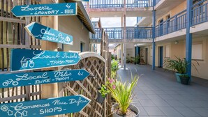 A courtyard with directional signs pointing to amenities such as a swimming pool, laundry, trash room, bike room, and shops. - Seaside Apartment in Biscarrosse (Biscarrosse)