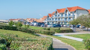 A hotel with multiple balconies, a parking lot, and well-maintained landscaping. - Seaside Apartment in Biscarrosse (Biscarrosse)