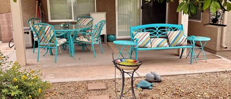 A patio with outdoor furniture, a table, and a bird bath.