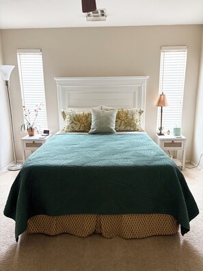 A bedroom with a large bed, two bedside tables, a lamp, and a potted plant. - 2-bedroom house in Active Adult Golf Course Community in Chandler (Chandler)