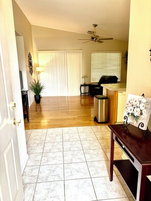 A living room with a ceiling fan, a black sofa, a coffee table, and a potted plant.