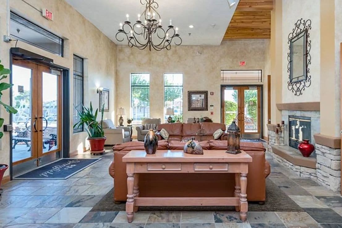 A lobby with a fireplace, a sofa, and a chandelier.