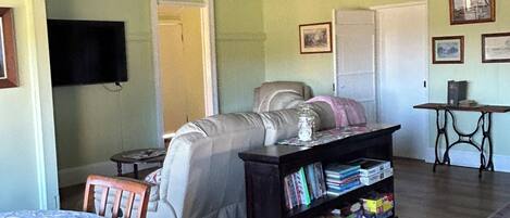 A living room with a sofa, a coffee table, a bookshelf, and a television.