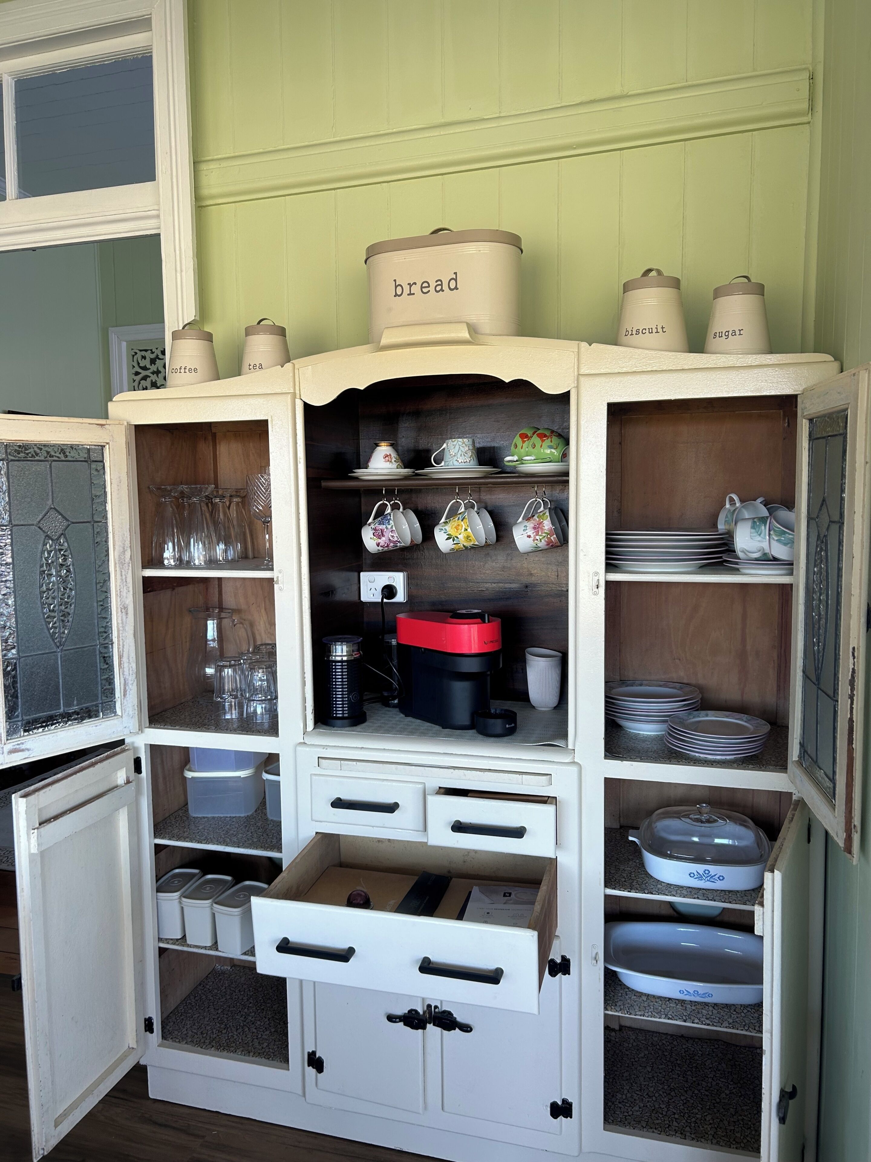 A kitchen cabinet with multiple compartments, including shelves for dishes and a section for kitchen appliances.