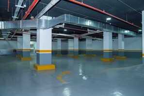 An indoor parking garage with multiple levels, concrete pillars, and overhead pipes. - Brai Hotel (Riyadh)