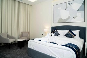 Ein Hotelzimmer mit einem Bett, zwei Sessel, einem kleinen Tisch und einem an der Wand hängenden abstrakten Gemälde.