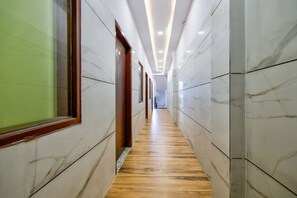 Un pasillo con paredes de mármol y suelo de madera, que conduce a una puerta al final.