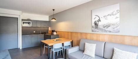 Un espacio moderno de estar con kitchenette, comedor y sofá.
