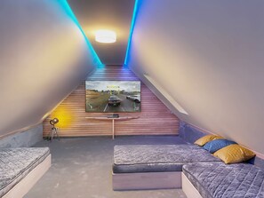 A room with a television on the wall, a bed, and a seating area. - Vacation Rental in a Half-Timbered House with a Sauna & Pool (Buschvitz)