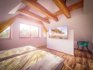 Ein Schlafzimmer mit einem Bett, einem Sessel, einem Gemälde und einem Fenster.