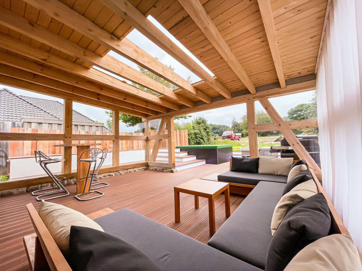 An outdoor patio with wooden beams, a sofa set, and a table.