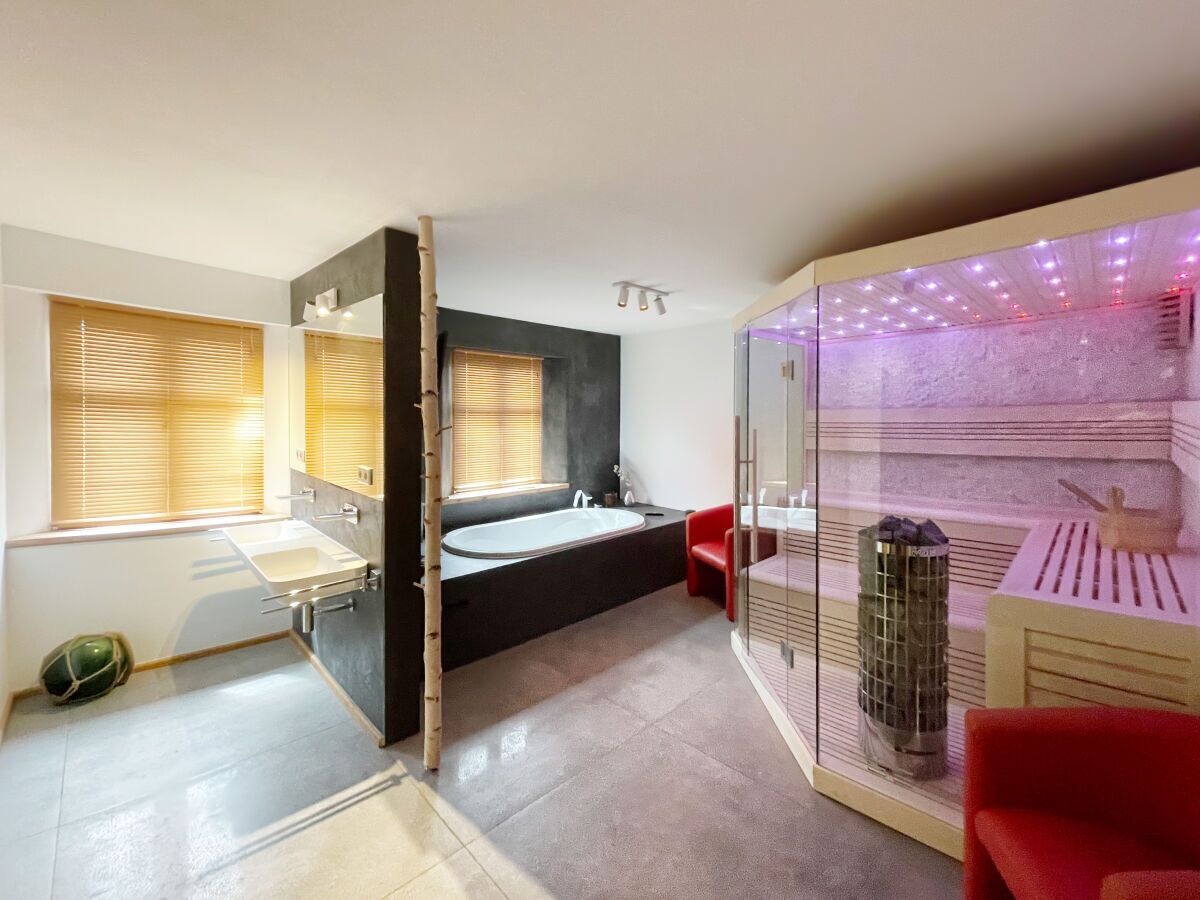 Une salle de bain moderne équipée d’une baignoire, d’une douche et d’un espace lavabo délimité par des parois en verre.