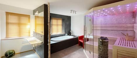 Een moderne badkamer met een bad, een douche en een badkamerinrichting met een glazen scherm.