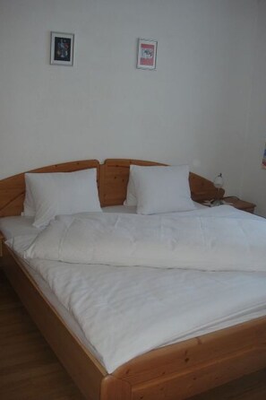 A single-bed room with a wooden headboard, white bedding, and two framed pictures on the wall. - Chasa Mezpra/Stephan Jenal Nr. 1, (Samnaun-Compatsch) by Interhome (Samnaun)