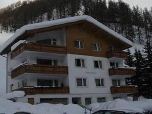 A multi-story hotel with balconies, a ski slope in the background, and a sign indicating 'Oberalpe.' - Chasa Mezpra/Stephan Jenal Nr. 1, (Samnaun-Compatsch) by Interhome (Samnaun)