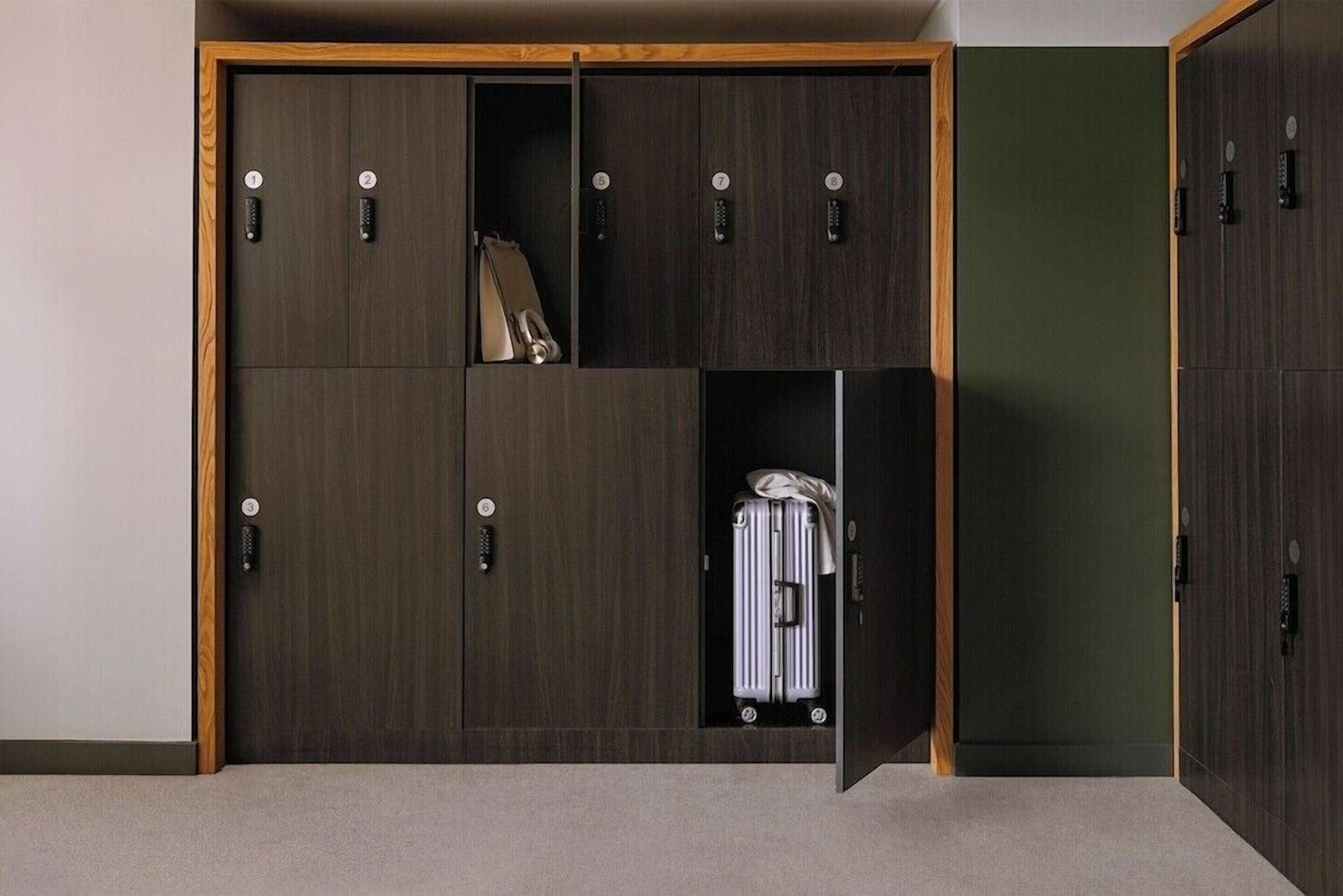 Een inloopkast met verschillende vakken, waarvan sommige ruimte hebben om kleding op te hangen, en een koffer zichtbaar in een van de onderste vakken.