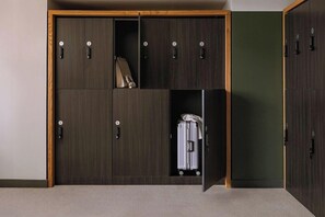 A wardrobe with multiple compartments, some with hanging space, and a suitcase visible in one of the lower compartments.