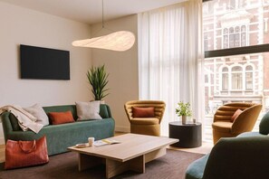 A modern living room with a sofa, armchairs, a coffee table, and a potted plant.