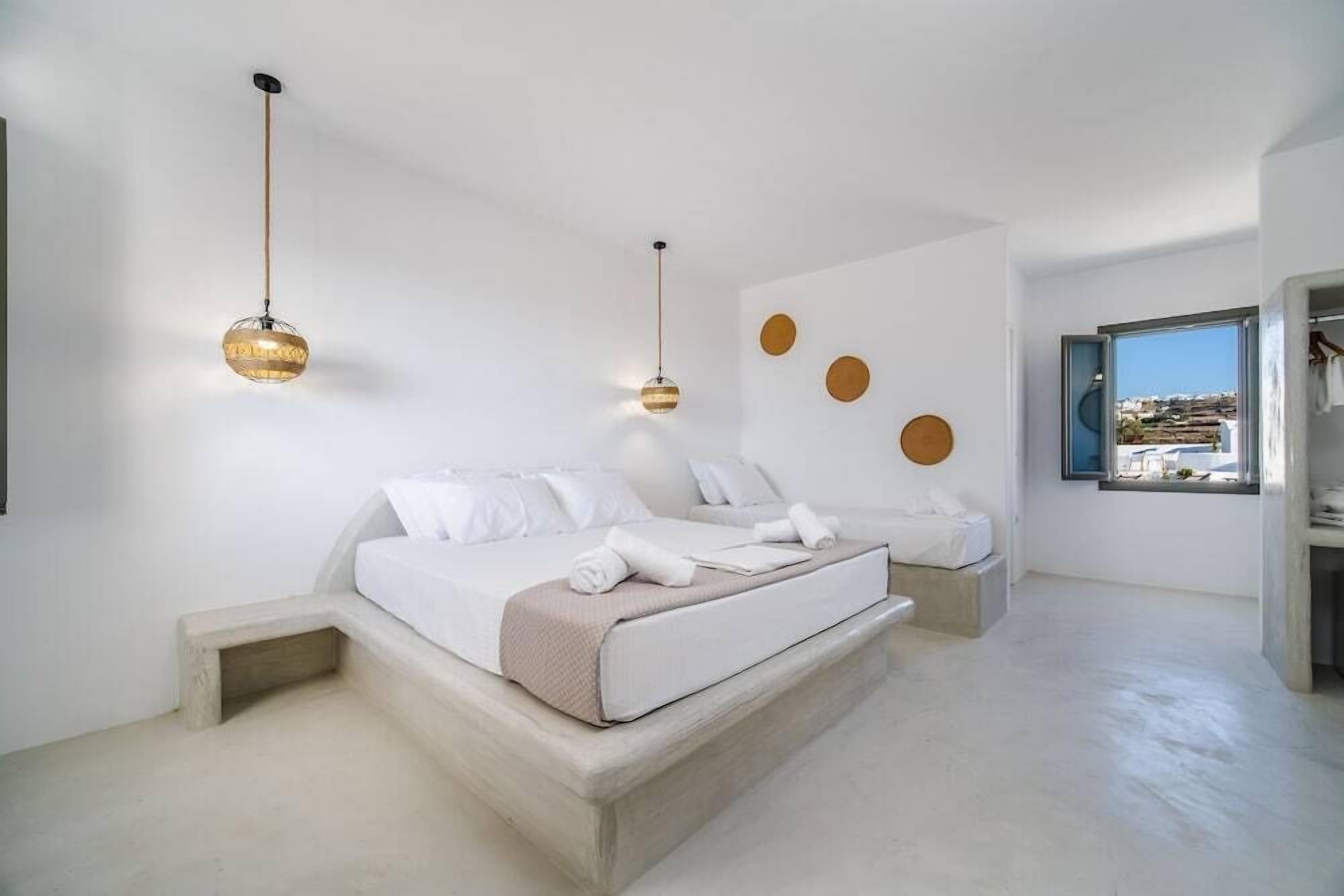 A modern bedroom with a large bed, two bedside tables, and a view of the city through a window.
