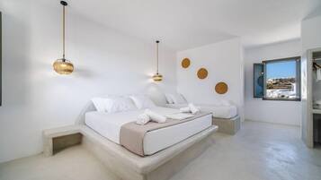 A modern bedroom with a large bed, two bedside tables, and a view of the city through a window.