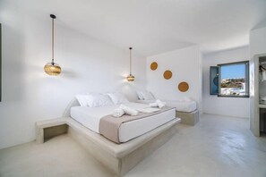 Ein modernes Schlafzimmer mit einem großen Bett, zwei Nachttischen und Blick auf die Stadt durch ein Fenster.
