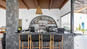 A bar area with stone pillars, a curved shelving unit for bottles, and a coffee machine.