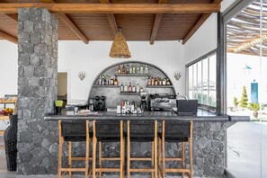 Eine Bar mit Säulen aus Stein, einer gebogenen Flaschenregal und einer Kaffeemaschine.
