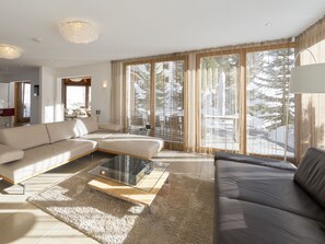 A modern living room with a sectional sofa, a glass coffee table, and large windows with curtains. - Apartments Grischuna Mountain Lodge, (Samnaun-Dorf) by Interhome (Samnaun)