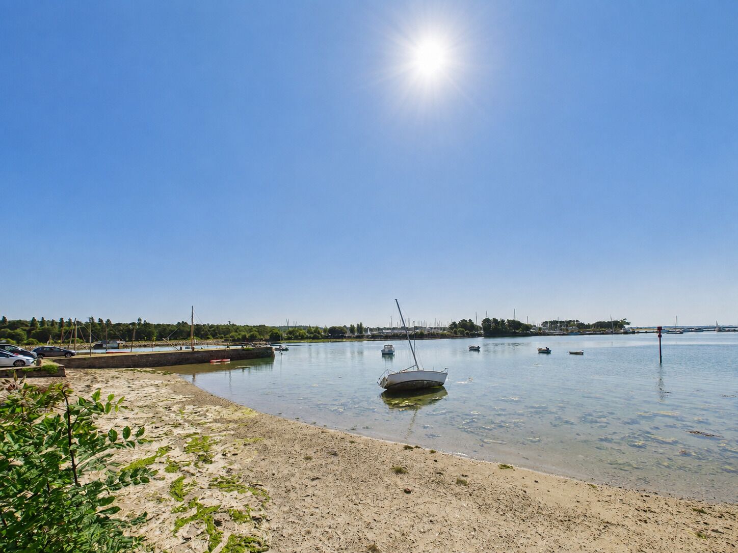 A beach with boats, a clear sky, and a calm sea.