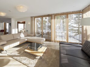 Ein modernes Wohnzimmer mit einer Couch, einem Hocker und einem Glastisch.