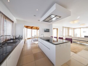 A modern kitchen with a central island, a dining area with a sofa, and a living room with a TV. - Apartments Grischuna Mountain Lodge, (Samnaun-Dorf) by Interhome (Samnaun)
