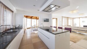 Una cucina moderna con isola centrale, un'area pranzo con divano e un soggiorno con un'ampia finestra.