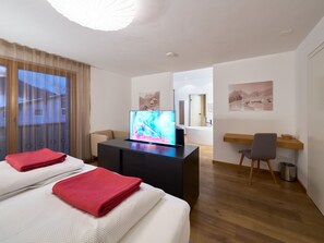 Quarto de hotel com cama, escrivaninha, televisão e obras de arte nas paredes.