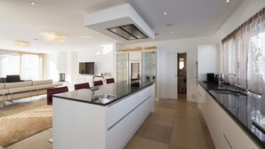 A modern kitchen with a central island, a dining area with a sofa, and a TV. - Apartments Grischuna Mountain Lodge, (Samnaun-Dorf) by Interhome (Samnaun)
