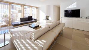 A modern living room with a sofa, a coffee table, and a TV mounted on the wall. - Apartments Grischuna Mountain Lodge, (Samnaun-Dorf) by Interhome (Samnaun)