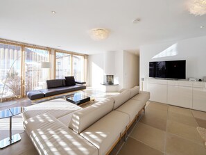 Ein modernes Wohnzimmer mit einer Couch, einem Couchtisch und einem an der Wand befestigten Fernseher.