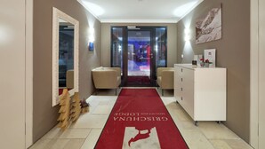 Ein Hotelkorridor mit rotem Teppich, einer Rezeption und Blick in den Zimmerbereich.
