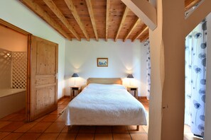 A bedroom with a wooden ceiling, a bed with a white bedspread, two bedside lamps, and a wooden wardrobe. - Charming estate for 14 people with a pool, lake, and private grounds (Arrosès)