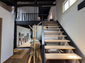 A multi-level interior with a staircase, wooden beams, and a ceiling with exposed beams.
